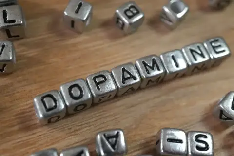 Cubos plateados forman la palabra "DOPAMINE". Descubre cómo aumentar tu dopamina para sentirte mejor.